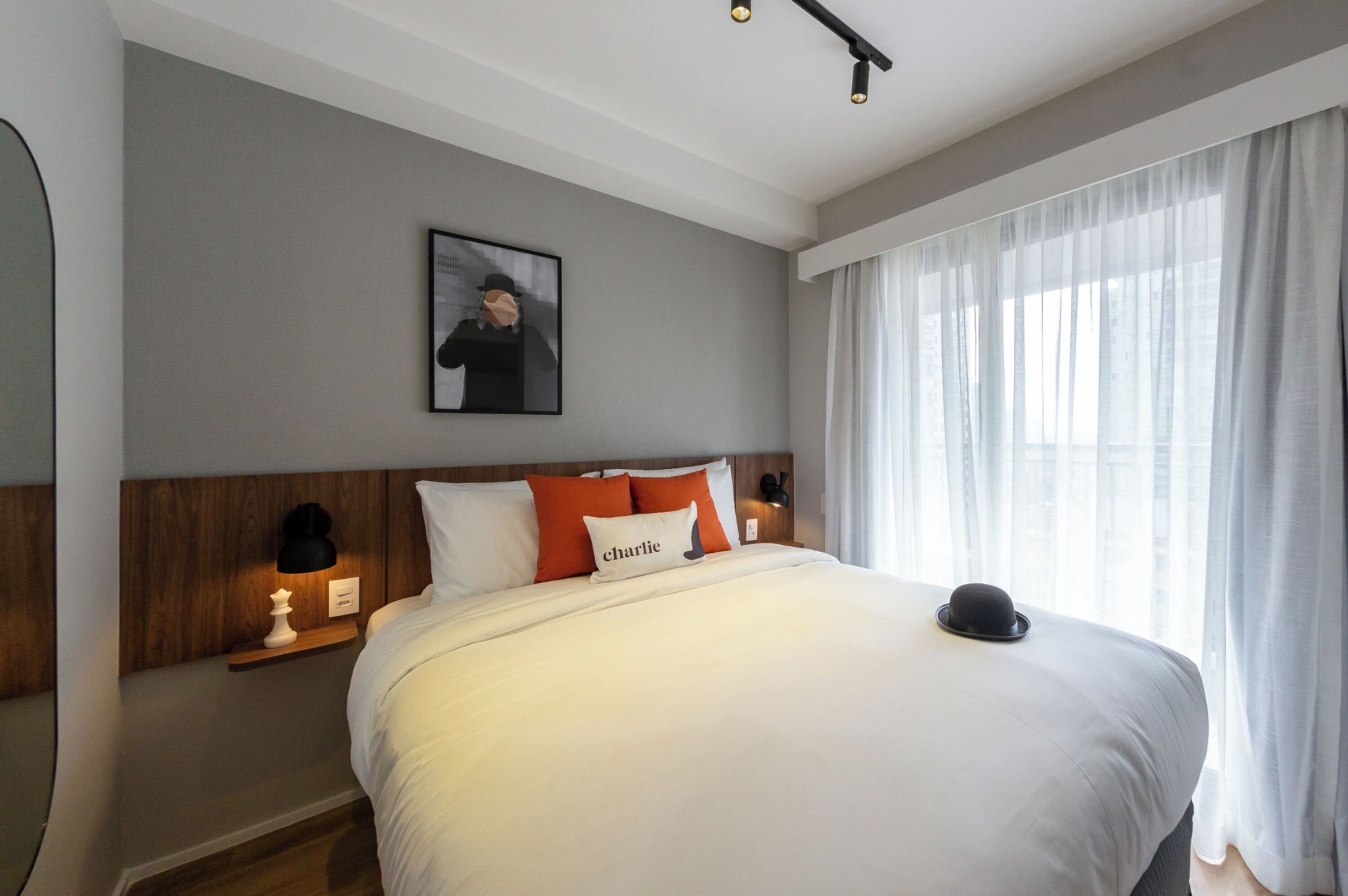 Una cama bien hecha con ropa de cama blanca y una almohada con la etiqueta "charlie".