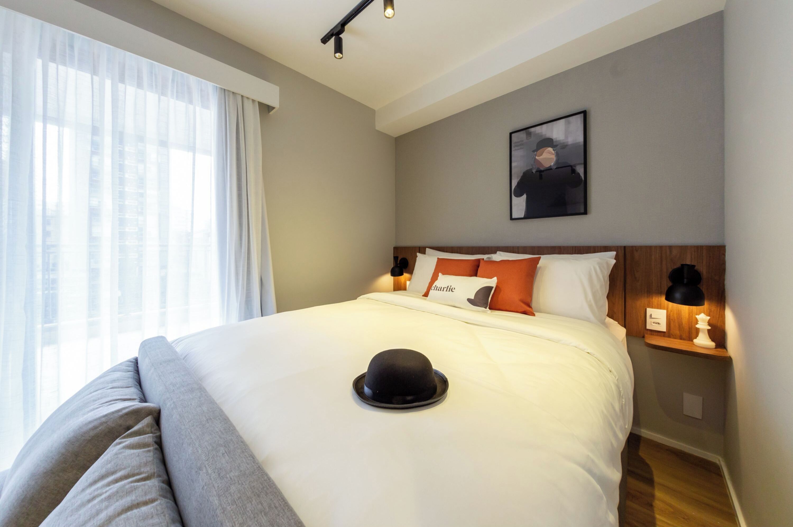 Una cama bien hecha con un sombrero encima, un almohadón con la palabra 