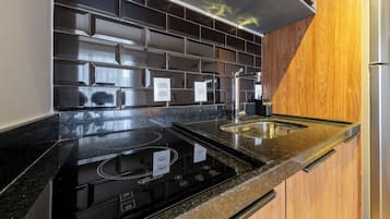 Una cocina con salpicadero de azulejos negros, electrodomésticos de acero inoxidable y armarios de madera.