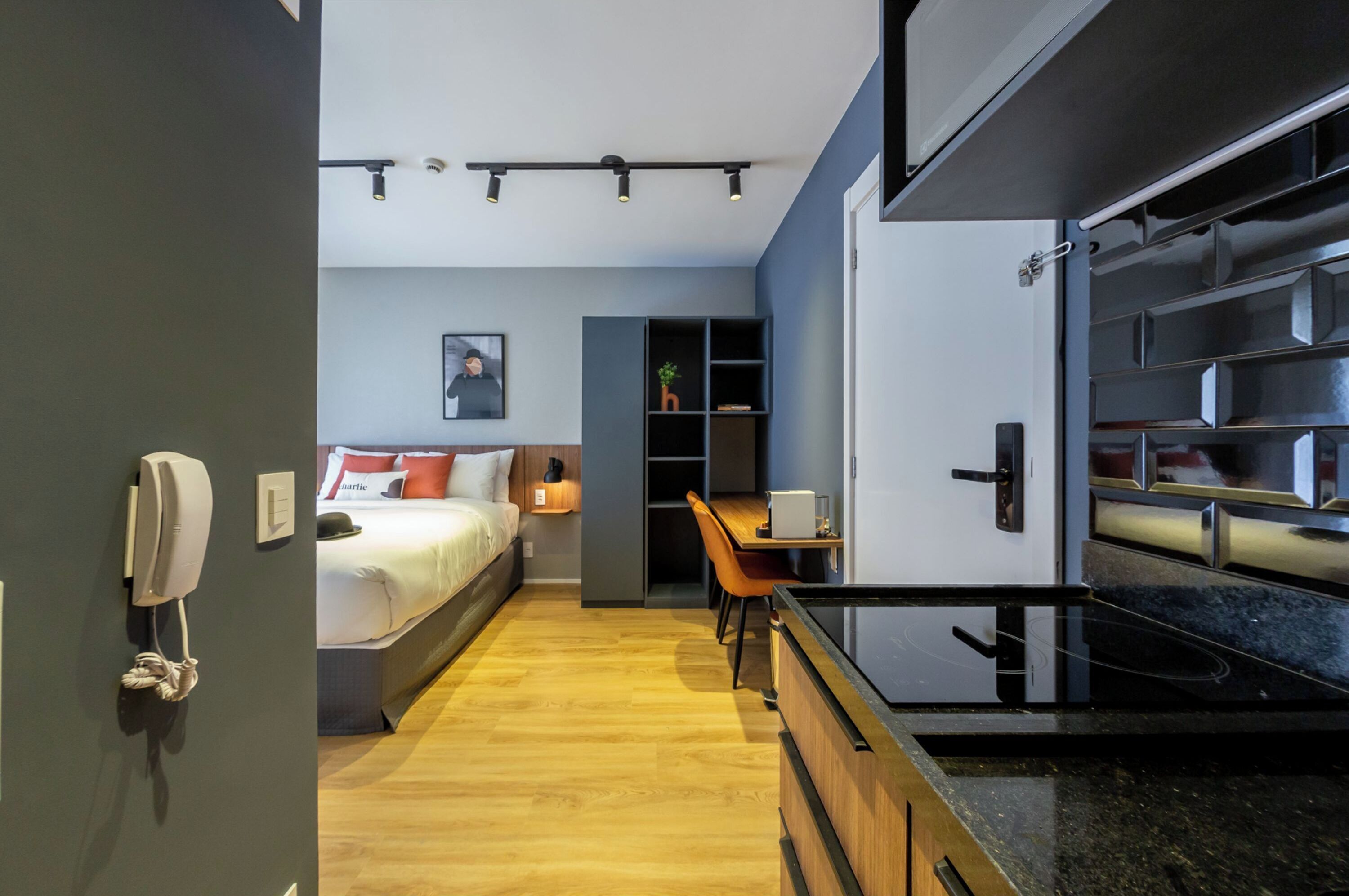 A modern hotel room with a bed, bedside table, and a small desk area.