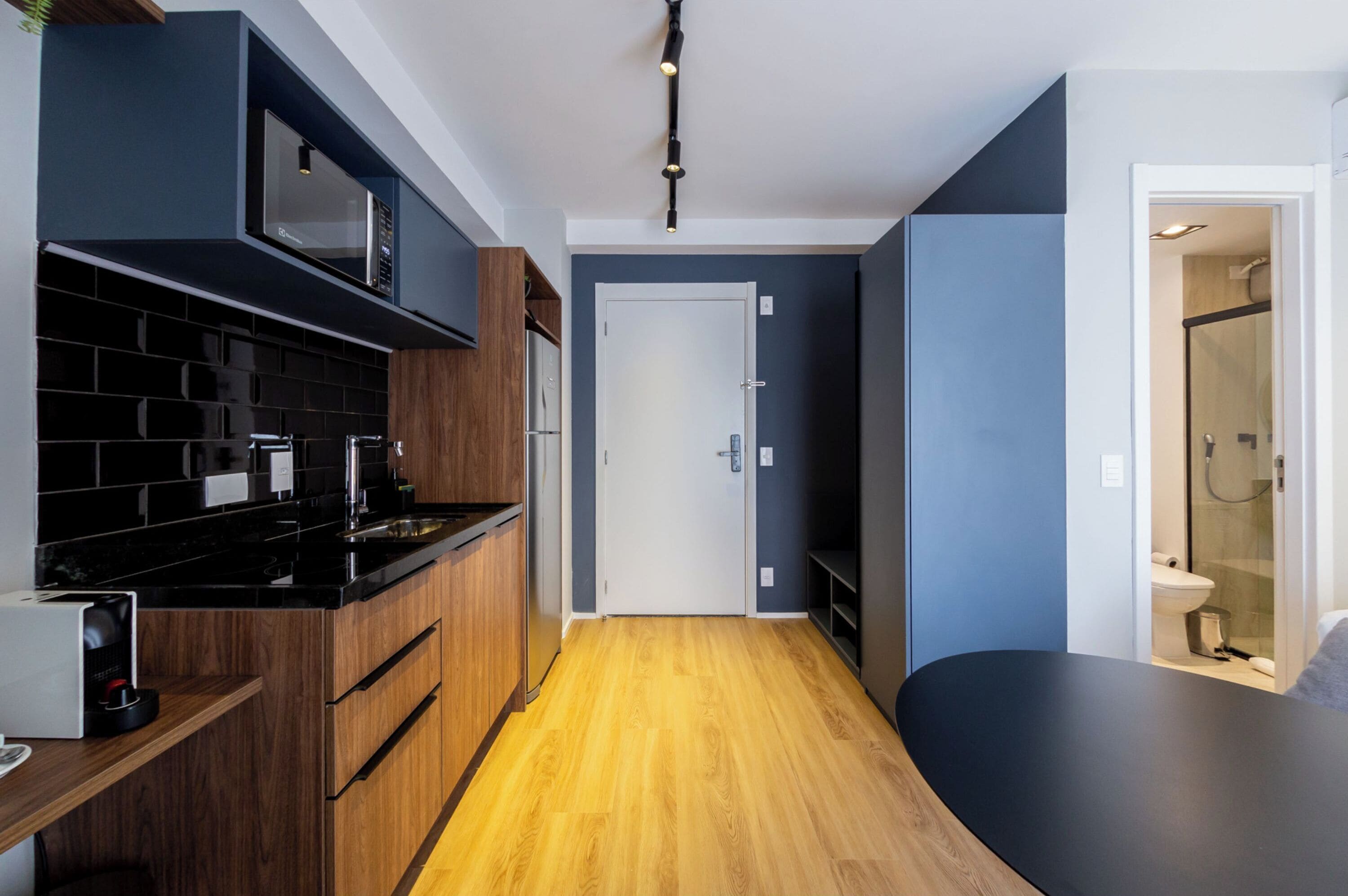 Eine moderne Küche mit schwarzen Arbeitsplatten, Holzschränken und einer Mikrowelle.