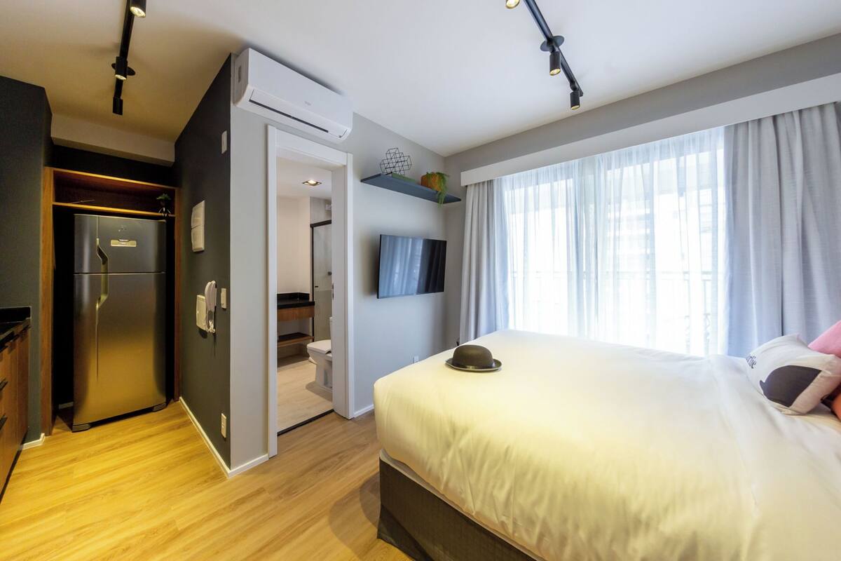 Ein modernes Hotelzimmer mit Bett, Fernseher, Kühlschrank und Bad.