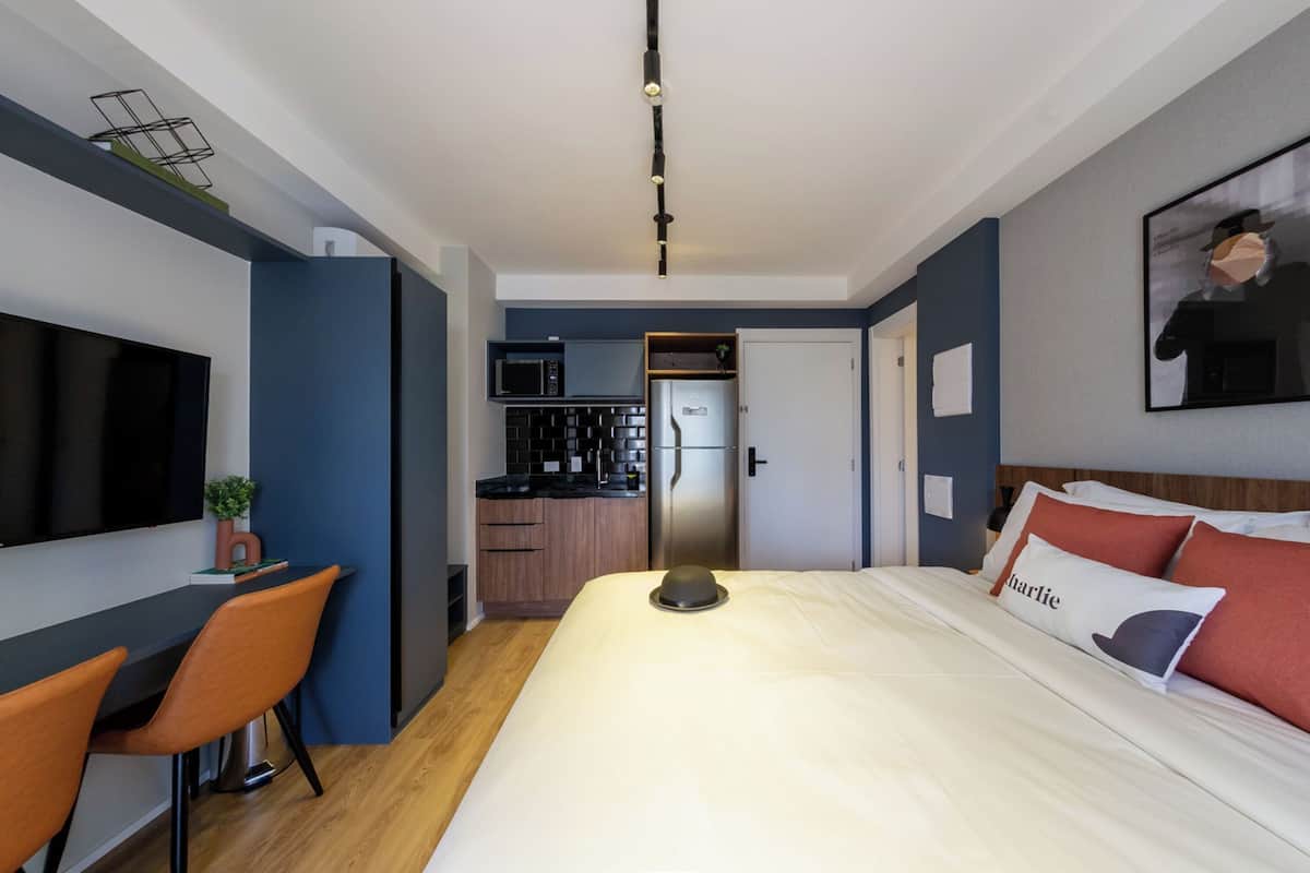 Ein modernes Hotelzimmer mit Bett, Schreibtisch und einer Küchenzeile.