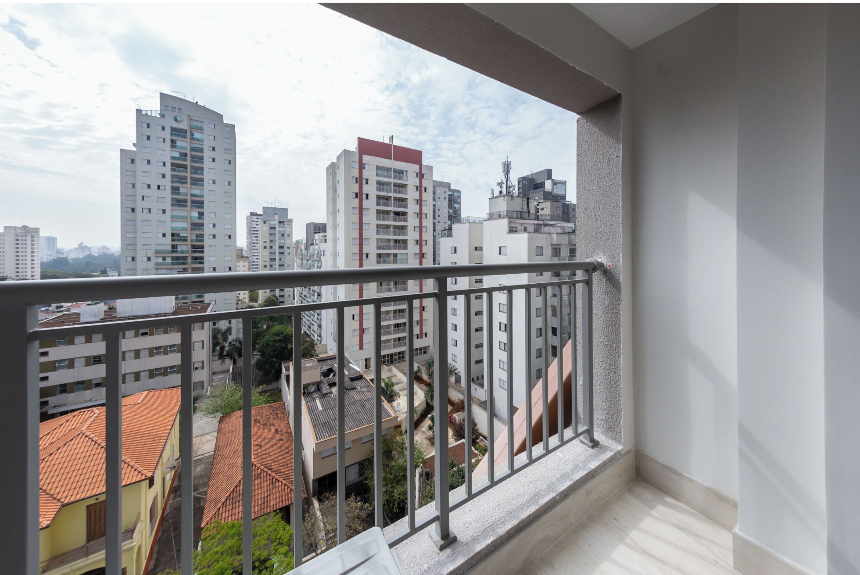 A balcony with a metal railing overlooking a cityscape with various buildings.