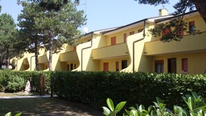 Una hilera de edificios amarillos con balcones, rodeados de vegetación y árboles.