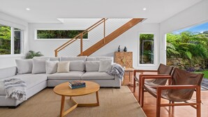 Een moderne woonkamer met een hoekbank, een houten salontafel en een trap.