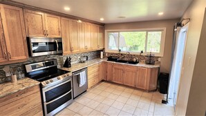 Une cuisine avec des meubles en bois, un four à micro-ondes, une cuisinière, un four et une fenêtre donnant sur un paysage verdoyant.