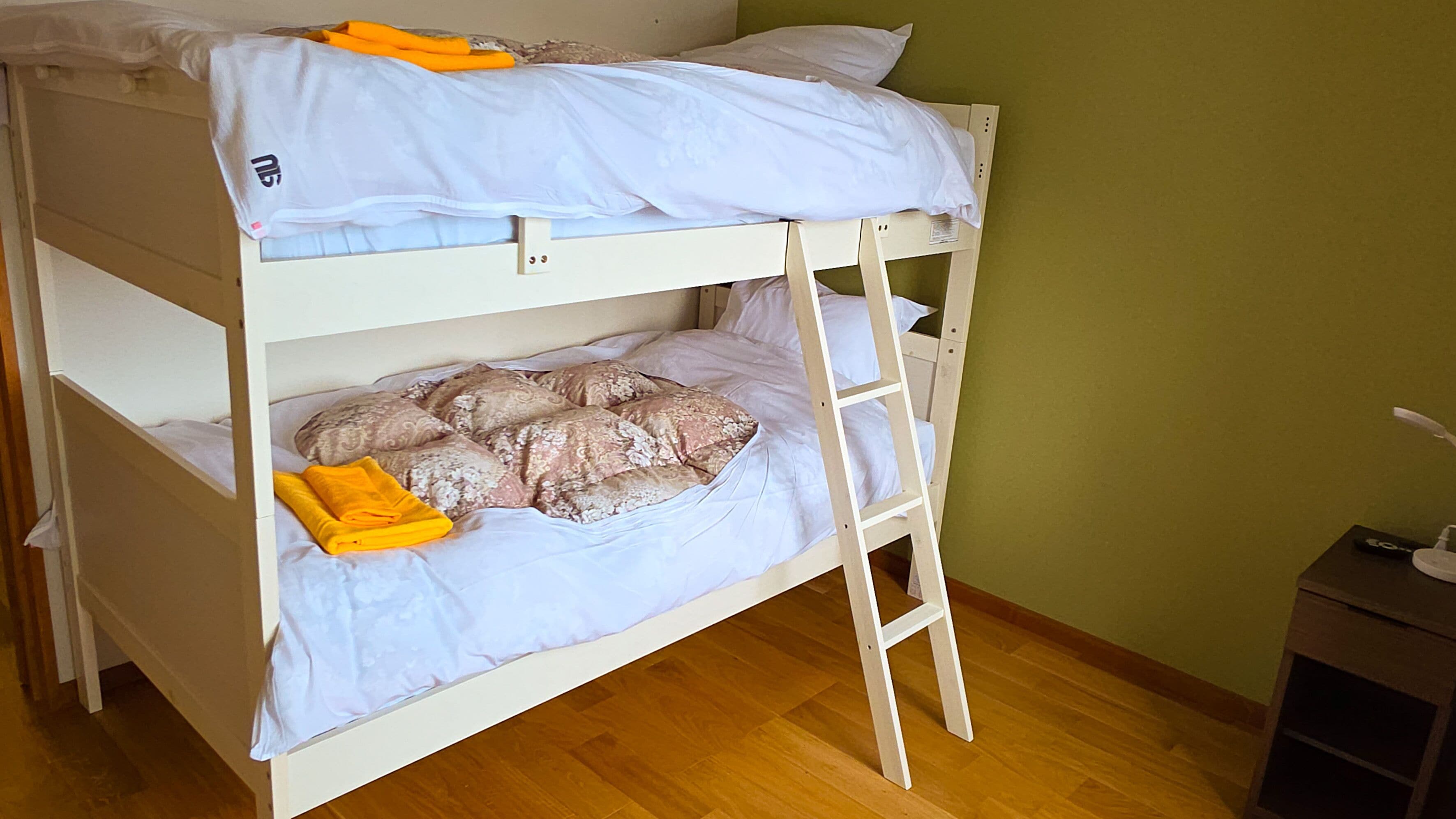 Een stapelbed met een ladder, kussens en een opgevouwen handdoek.
