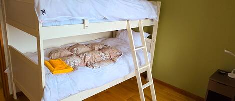 Una cama litera con escalera, almohadas y una toalla doblada.