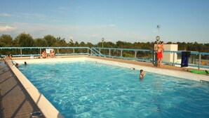 A swimming pool with clear blue water, surrounded by a tiled deck and a metal railing. - Nice Flat in a Residence With Swimming Pool - By Beahost Rentals (San Michele al Tagliamento)