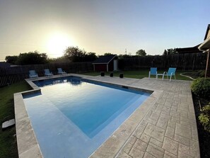 A rectangular swimming pool with a tiled deck, surrounded by a wooden fence, and a small shed in the background. - Spacious Home. Pool. Hot Tub. Grill. Pool Table. 4 Bed. 2 Bath. (Watauga)