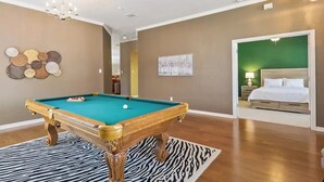 A room with a pool table, a zebra-patterned rug, a bed with a green wall, and a chandelier. - Spacious Home. Pool. Hot Tub. Grill. Pool Table. 4 Bed. 2 Bath. (Watauga)
