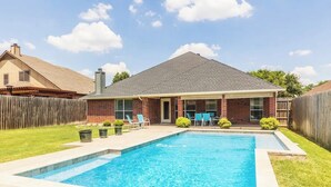 A backyard with a swimming pool, a covered patio, and a brick house. - Spacious Home. Pool. Hot Tub. Grill. Pool Table. 4 Bed. 2 Bath. (Watauga)