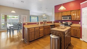 A spacious kitchen with wooden cabinets, a central island, and a dining area with a table and chairs. - Spacious Home. Pool. Hot Tub. Grill. Pool Table. 4 Bed. 2 Bath. (Watauga)