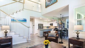 A spacious living area with a wooden coffee table, a sofa, and a dining table with chairs. A staircase leads to an upper level. - 2 - bedroom Waikoloa Townhouse 106, close to beaches and restaurants (Waikoloa Village)