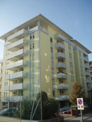 Un immeuble à plusieurs étages doté de balcons, d’un panneau indiquant qu’il est interdit de se garer et d’une entrée fermée par un portail.