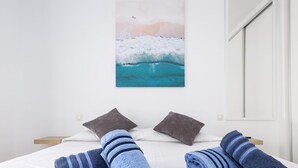 Une chambre d’hôtel avec un lit, deux oreillers et deux serviettes enroulées.