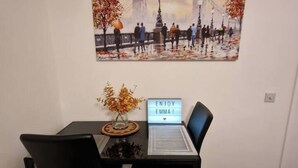 A dining table with a vase of autumn leaves, a sign that reads "ENJOY EMMA!", and a painting of a cityscape on the wall. - 1 Bed Flat Sleeps 2 with Free Parking & Patio (London)