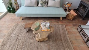 Ein Wohnzimmer mit einem hellblauen Sofa, zwei Kissen, einem Holztisch mit einer Zeitschrift, einer Kerze und einem Glas.