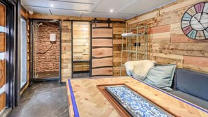 Ein Zimmer mit Holzwänden, einer Uhr, einem Sofa und einem Glastisch.