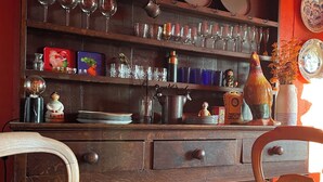 A wooden cabinet with shelves holding various glassware, plates, and decorative items. - Chalet mountain and dog friendly, hot tub (Bourg-Saint-Maurice)