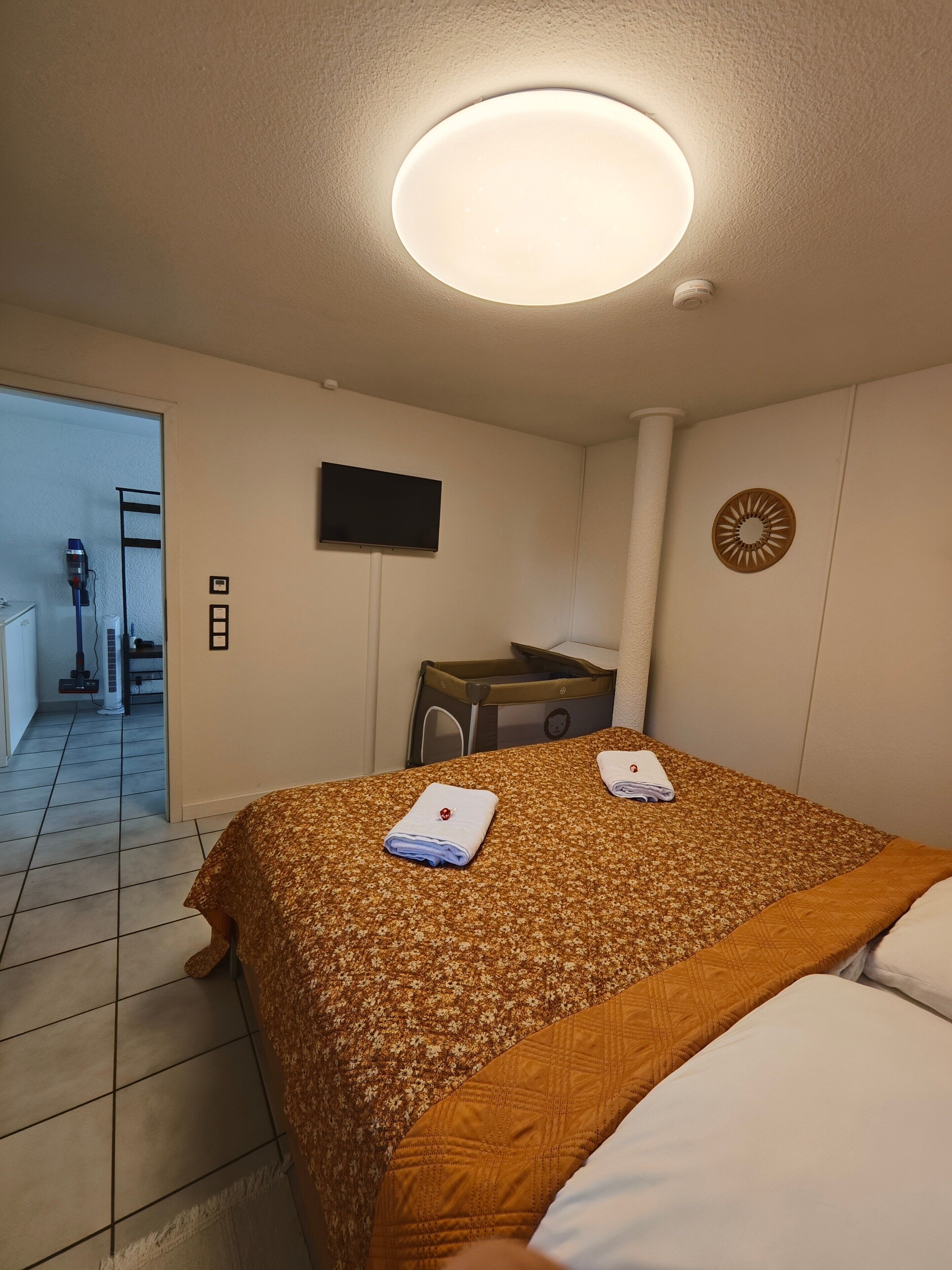 A hotel room with a bed, a desk, a television, and a bathroom visible through an open door.