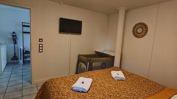 A hotel room with a bed, a desk, a television, and a bathroom visible through an open door.