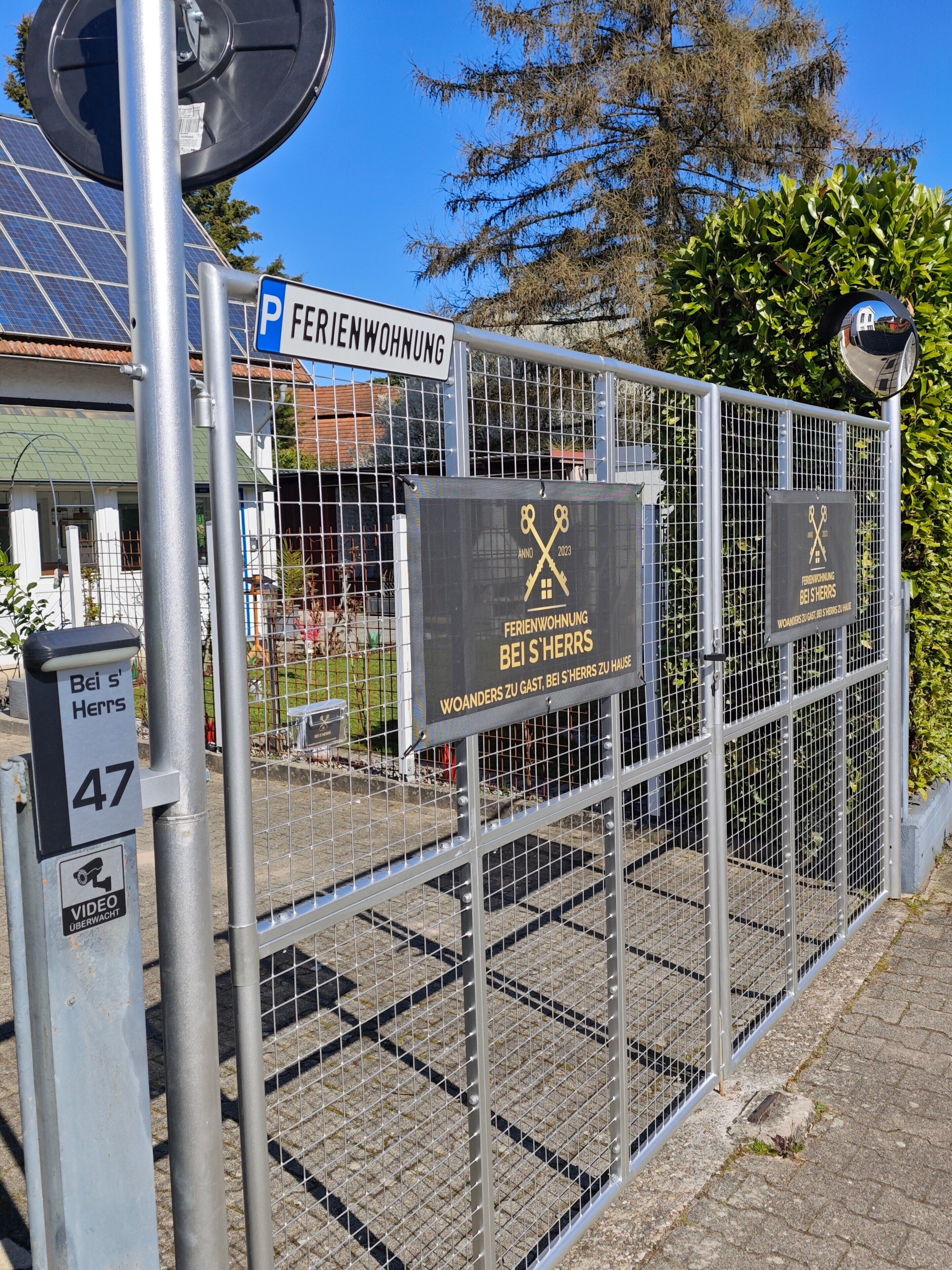 A gated area with a sign indicating 'Feriendorfwohnung bei S'Herrs' and a parking sign.