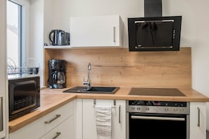 A modern kitchen with a microwave, coffee maker, sink, and oven.