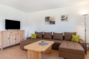 A modern living room with a sofa, a coffee table, a TV, and a cabinet.
