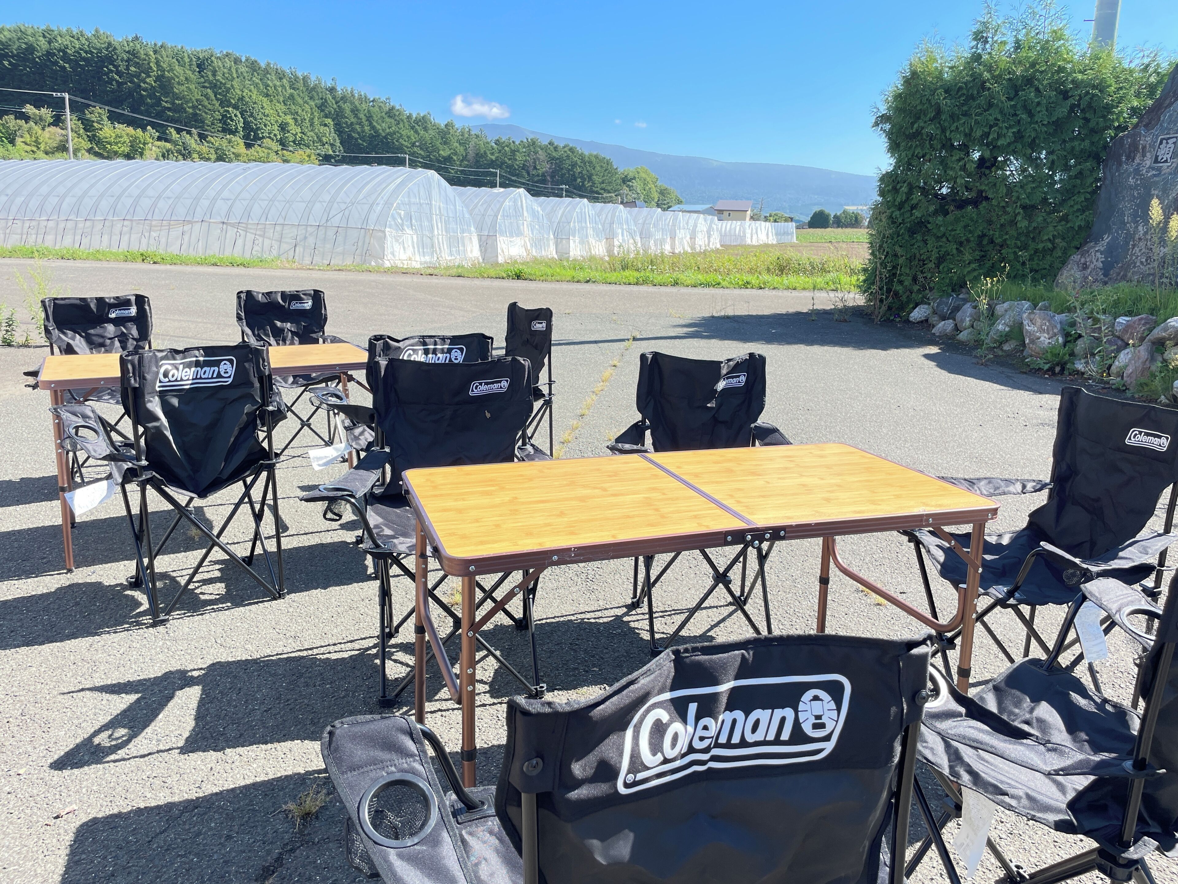 An outdoor seating area with tables and Coleman-branded folding chairs.