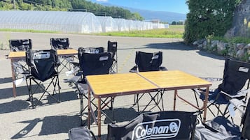 An outdoor seating area with tables and Coleman-branded folding chairs.