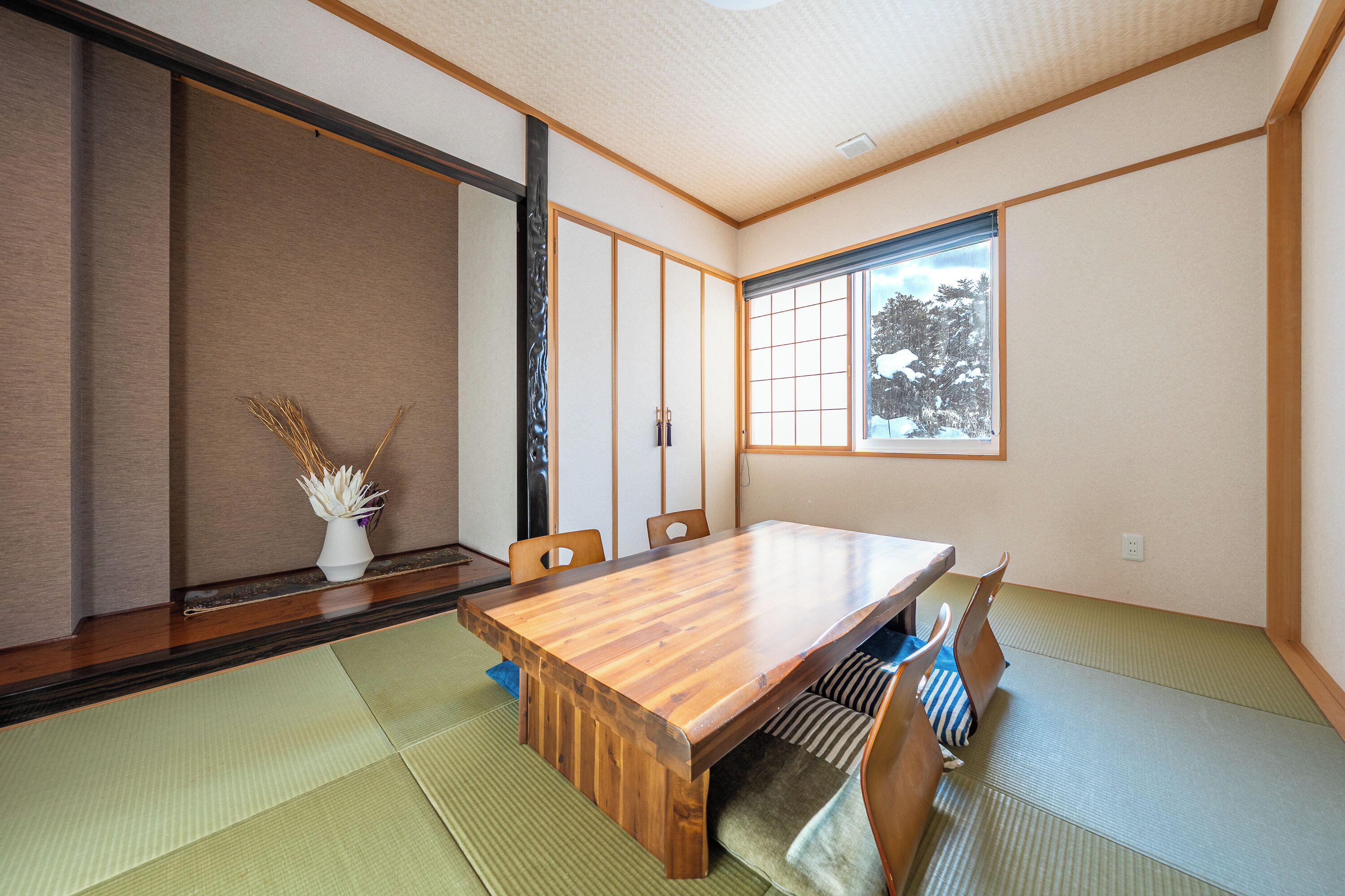 Una habitación japonesa tradicional con suelo de tatami, una mesa de madera para comer y biombos shoji.