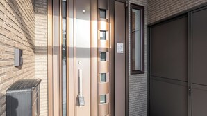 Une entrée moderne avec une porte en verre, un portail en métal et un mur en briques.