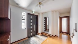 Un couloir avec un banc en bois, une porte dotée d’un miroir et un luminaire au plafond.