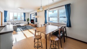 Un salon moderne avec un canapé, un téléviseur et un coin repas.
