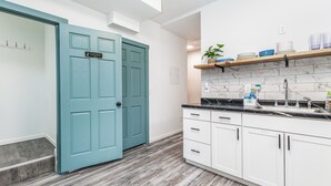 A modern kitchen with white cabinets, a teal door, and a marble backsplash. - 1103#203 / Downtown Oasis: En-Suite Master (Dubuque)