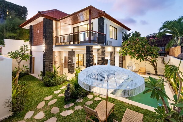 A two-story house with a balcony, a circular outdoor seating area, and a small pool. - Villa Ambalika by Villa Finder (Seminyak)