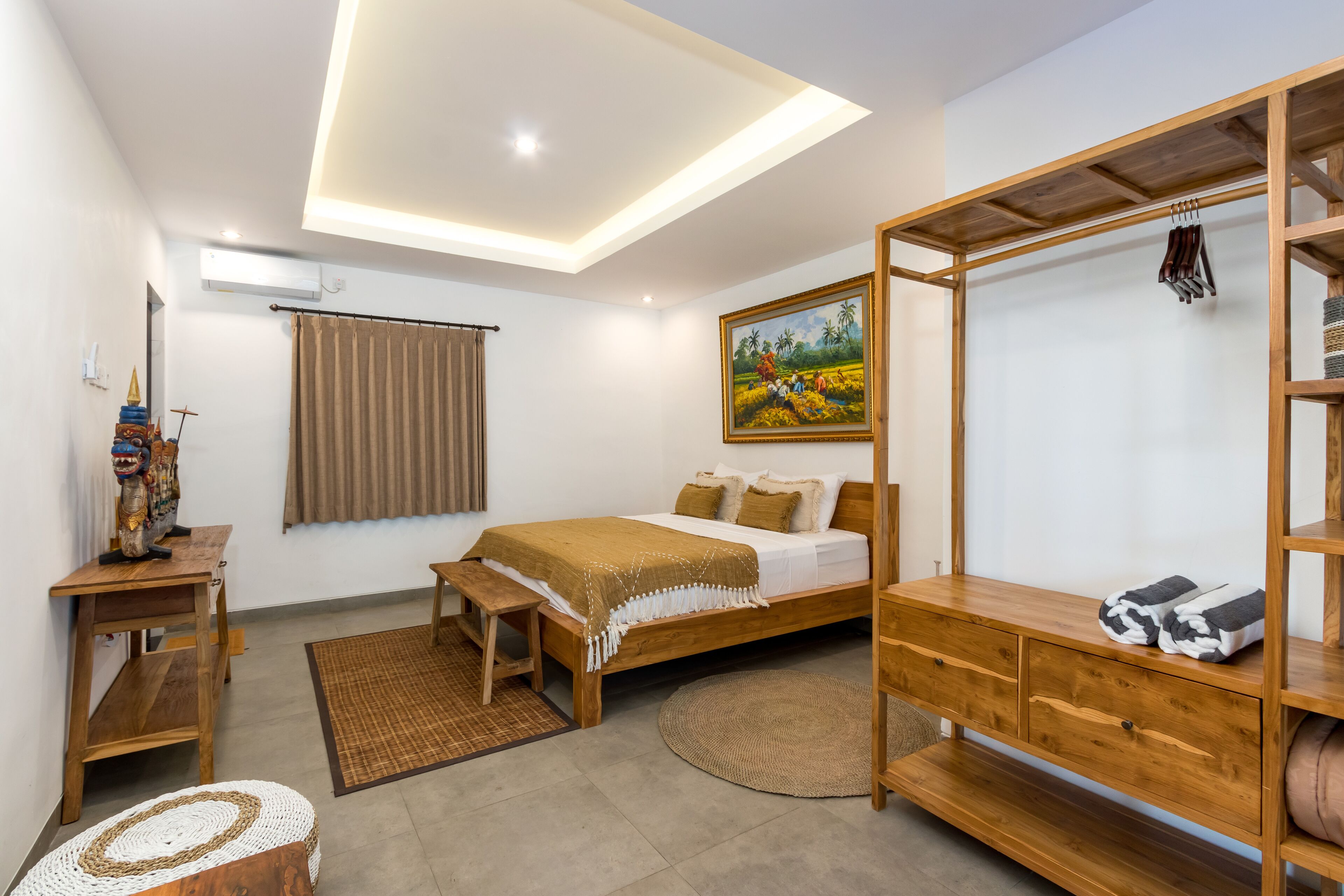 Een moderne slaapkamer met een houten bed, een bankje, een klein tafeltje en een plank met handdoeken.