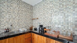 Une cuisine avec un dosseret de carrelage à motifs, des armoires en bois, un plan de travail noir et divers appareils de cuisine.