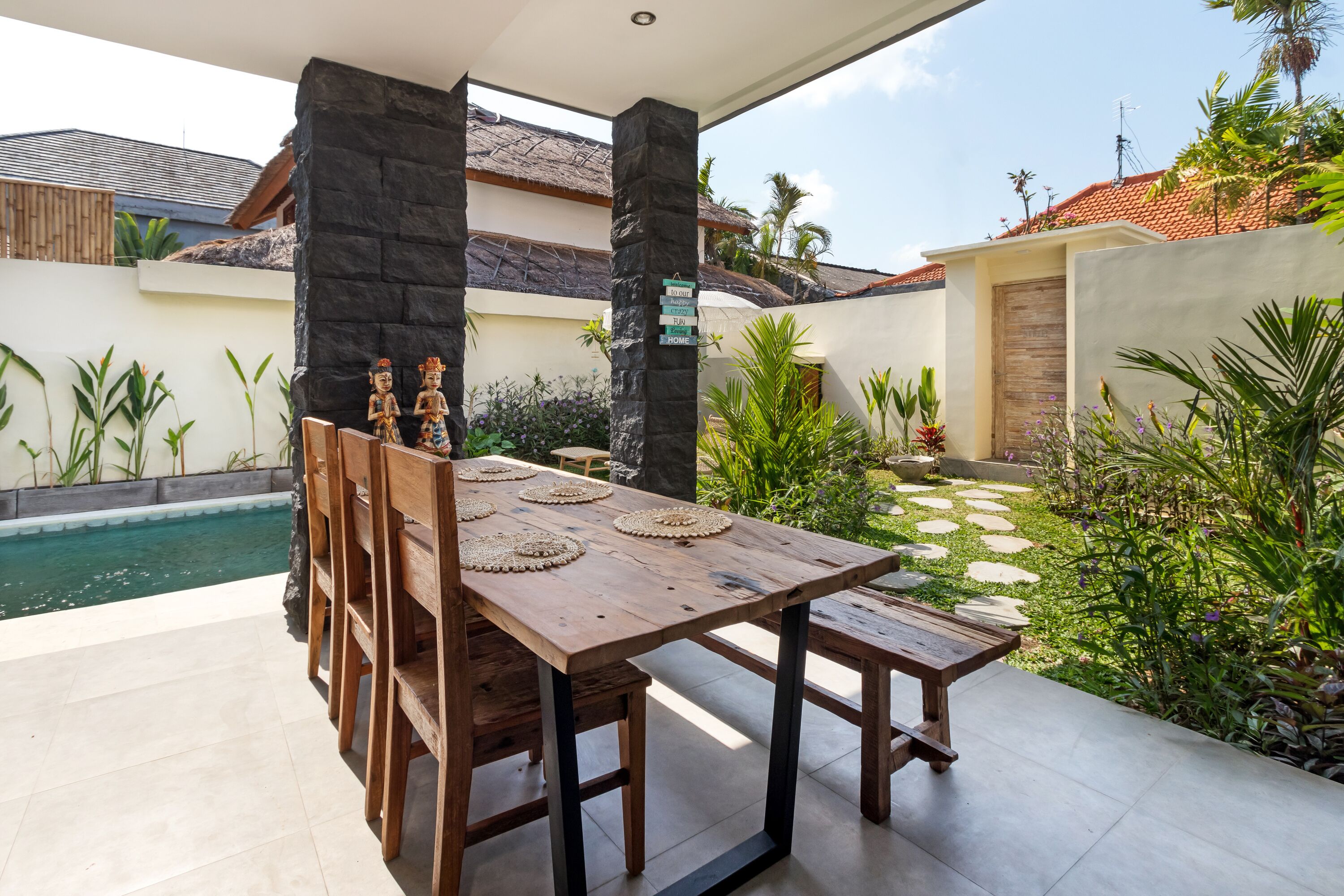 A wooden dining table with chairs, a stone pillar, and a sign indicating 'Home'.