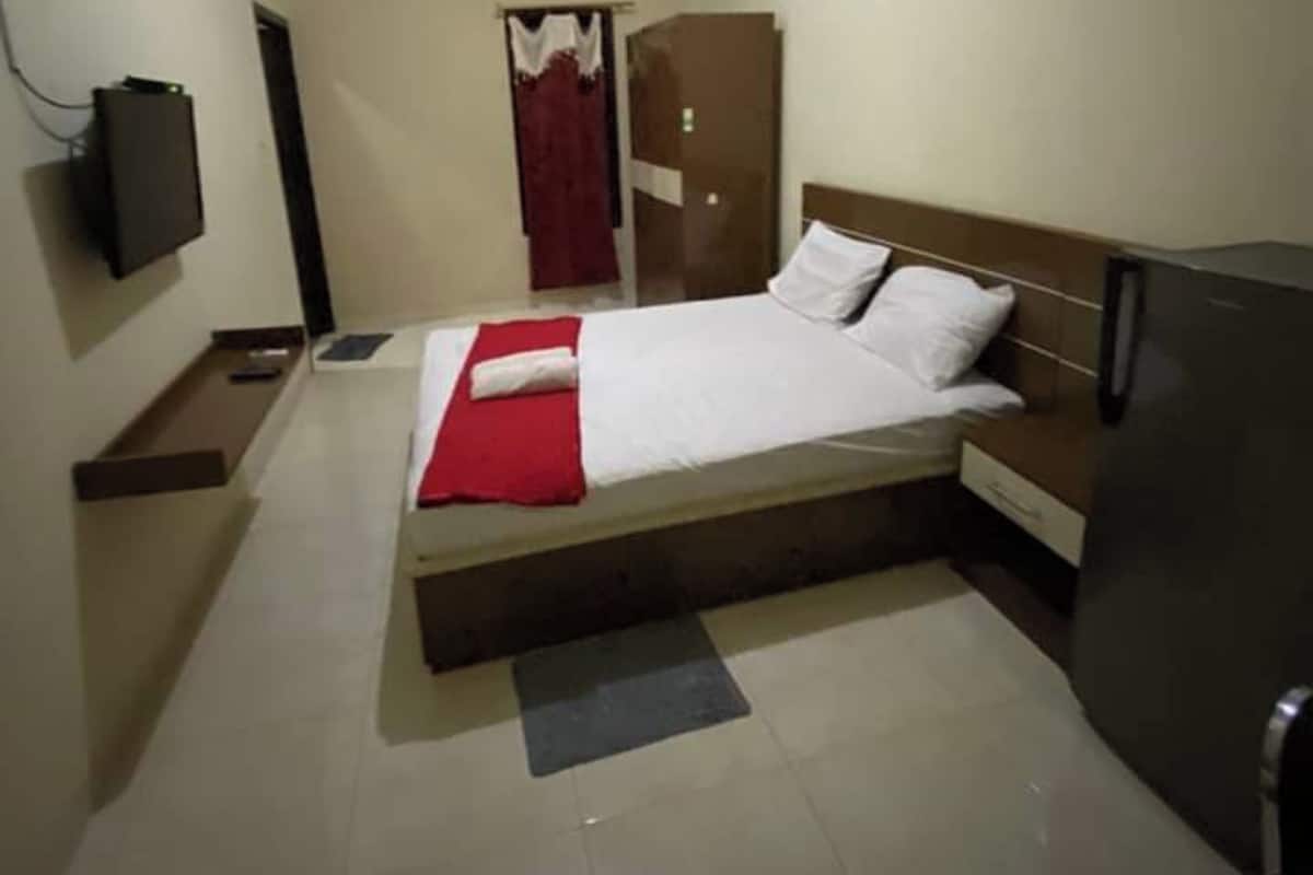 Quarto com cama, televisão, guarda-roupa e secretária.