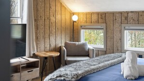 Een kamer met een bed, een stoel, een tafeltje en een televisie.