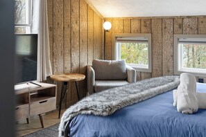 A room with a bed, a chair, a small table, and a television.