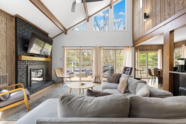 Un salón amplio con chimenea, ventanas grandes y un techo alto.