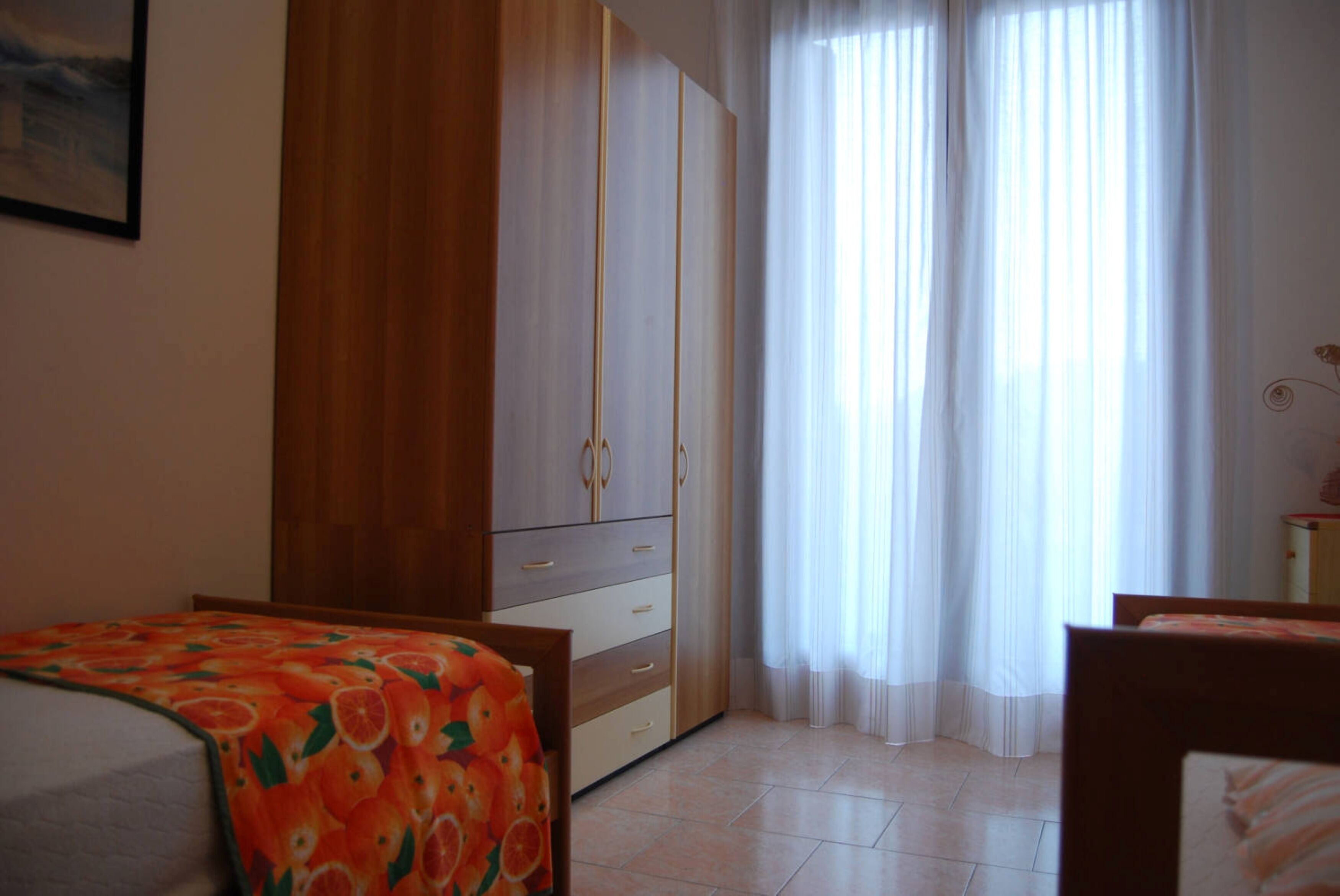 Une chambre à coucher avec un lit, une armoire et une fenêtre avec des rideaux.
