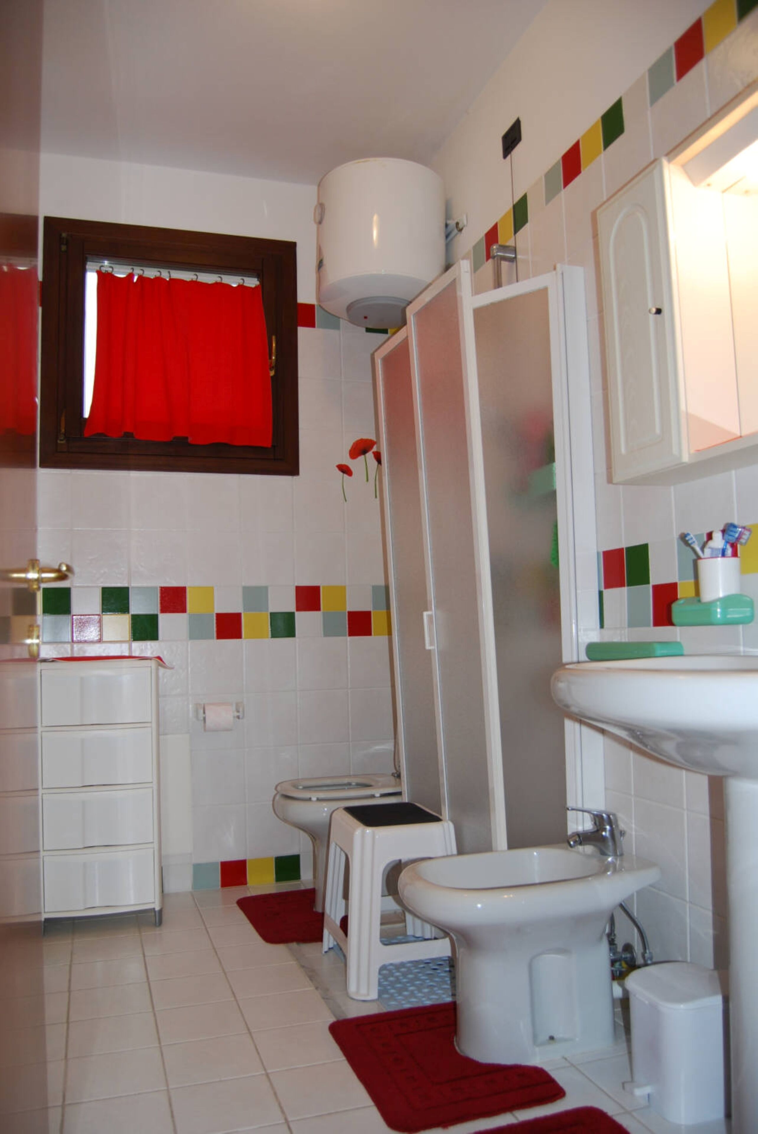 Et badeværelse med toilet, bidet, vask og et spejl.