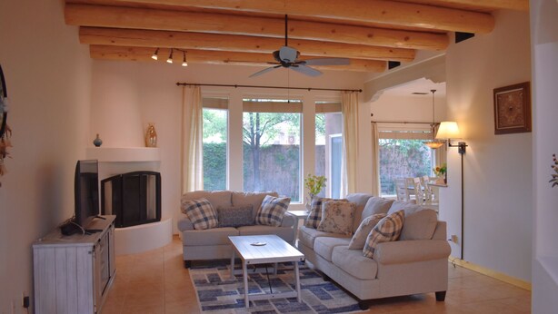 A living room with a fireplace, two sofas, a coffee table, and a ceiling fan. - Rio Oasis with Southwest charm (Albuquerque)