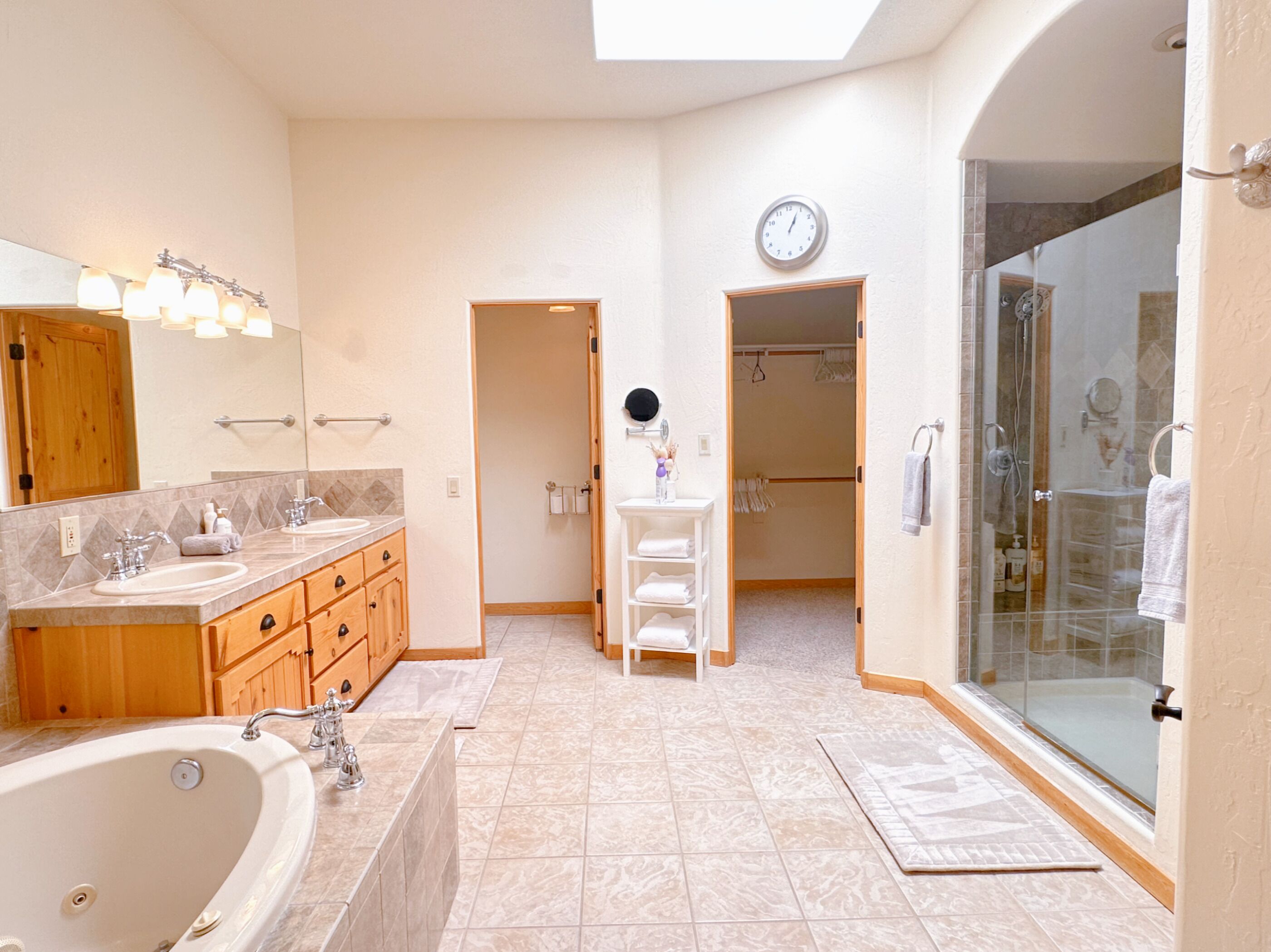 A spacious bathroom with a large bathtub, a walk-in shower, and a vanity with a mirror and lights.