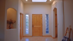 A hallway with a wooden door, a skylight, and a vase with dried flowers. - Rio Oasis with Southwest charm (Albuquerque)